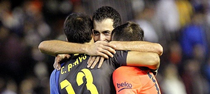 Claudio Bravo (vlevo) a Jordi Alba objímají Sergia Busquetse, který pozdním gólem rozhodl o výhře Barcelony nad Valencií