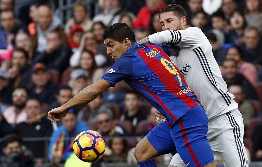 Obránce Realu Madrid Sergio Ramos se snaží všemi možnými prostředky dostat k míči přes útočníka Barcelony Luise Suáreze ve šlágru španělské ligy.
