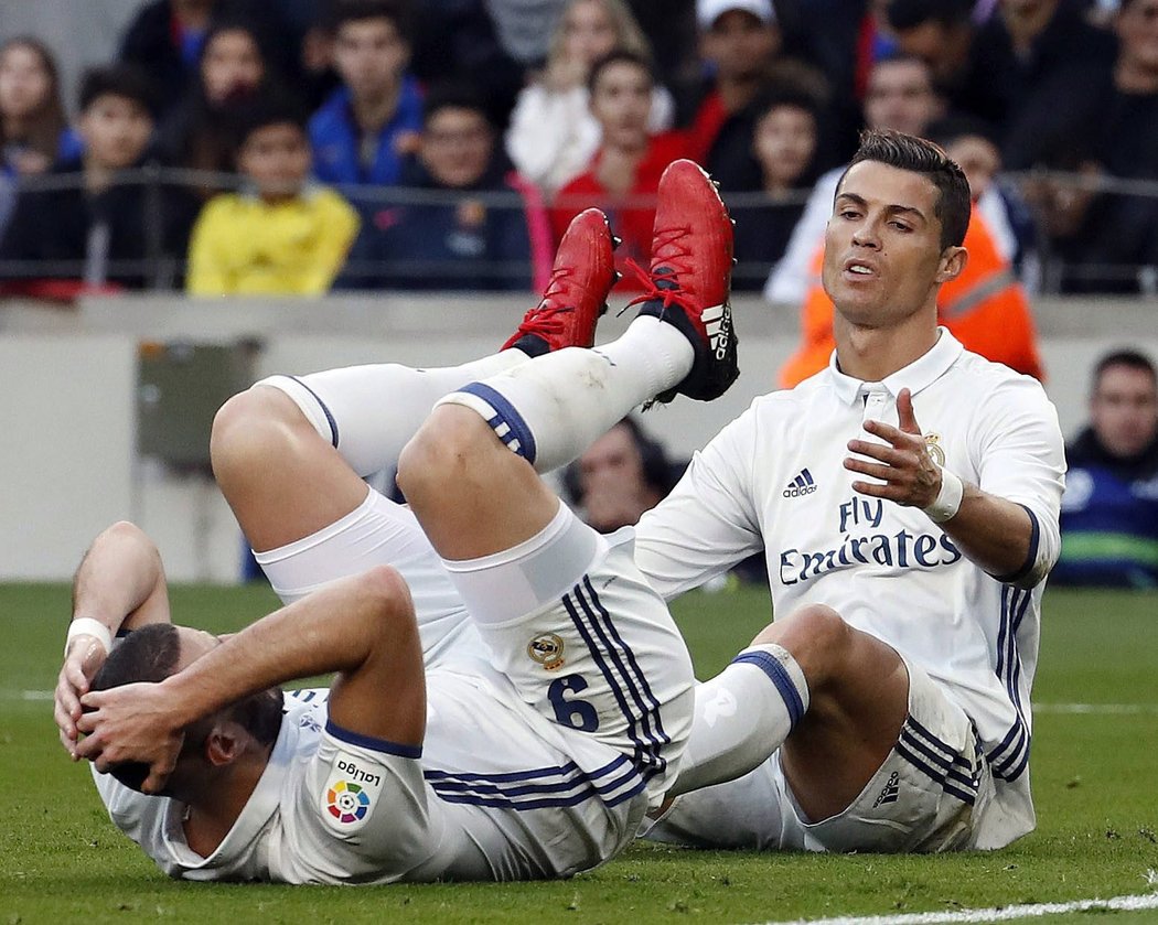 Útočník Realu Madrid Benzema je na zemi po srážce se spoluhráčem Cristianem Ronaldem. Na barcelonském trávníku to madridskému týmu moc neladilo.