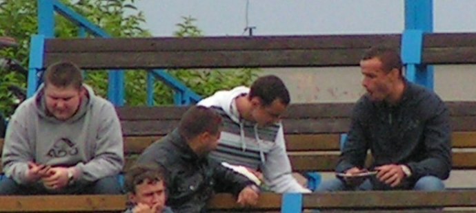 Jiří Kladrubský a Erich Brabec se při zápase divize A ládují klobásami. Muž v šedivé mikině jim pro ně chodil.