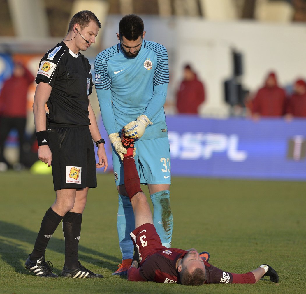 Brankář Sparty Tomáš Koubek pomáhá spoluhráči Michalu Kadlecovi s křečí