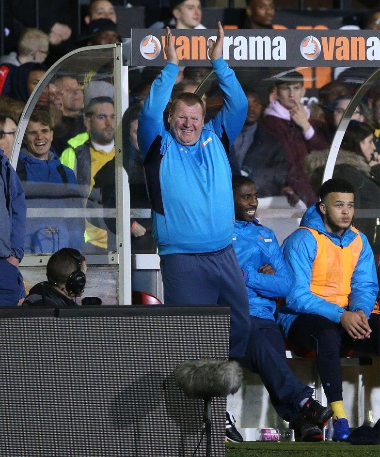 Rezervní brankář Suttonu Wayne Shaw aplauduje fanouškům, kteří reagovali, když se přímo na lavičce zakousl do bagety.