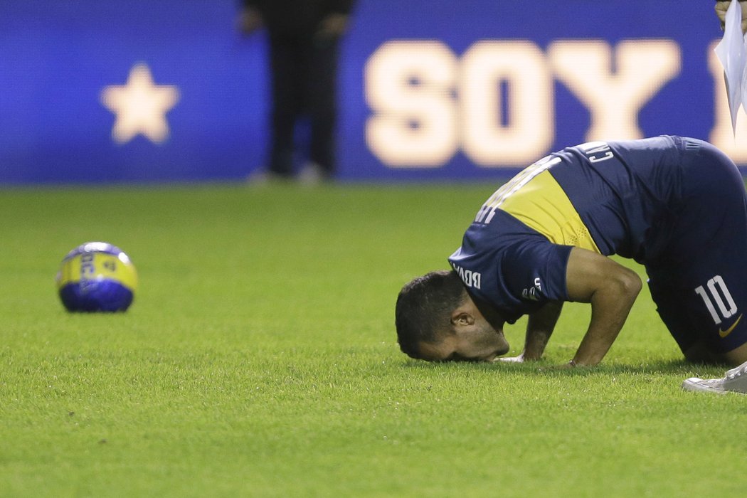 Útočník Carlos Tévez líbá trávník na stadionu Bombonera po návratu do klubu Boca Juniors