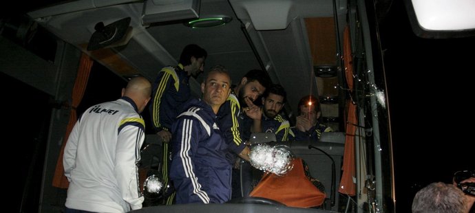 Vyděšení fotbalisté a trenéři Fenerbahce Istanbul sledují prostřílené čelní a boční sklo svého autobusu po útoku (archivní foto)