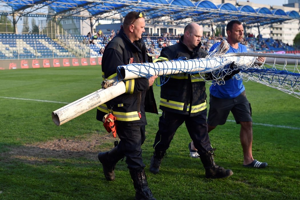 Zlámalem zlomená tyč odnášená ze stadionu za pomoci hasičů