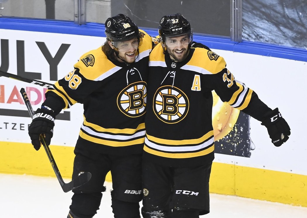 David Pastrňák (vlevo) a Patrice Bergeron (vpravo) se radují ze vstřelené branky Bostonu v pátém utkání Caroliny