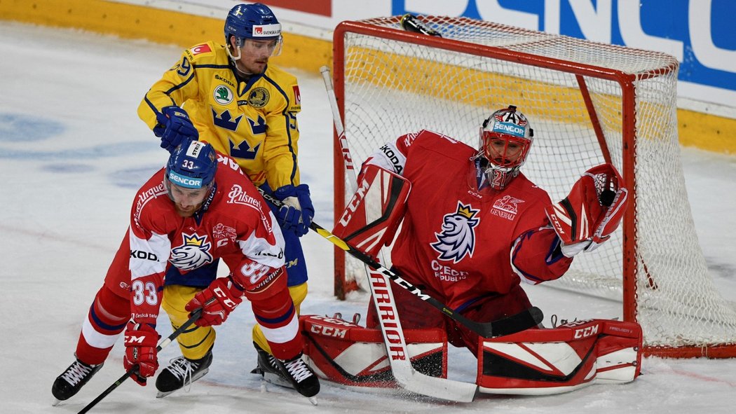 Český brankář Jakub Kovář (vpravo) chytá puk do lapačky. Před ním bojují švédský útočník Linus Johansson a český obránce Jakub Nakládal