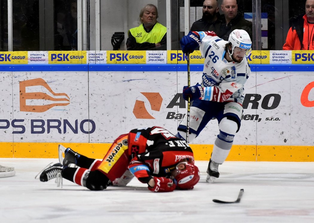 Hradecký obránce Filip Pavlík leží v bolestech na ledě u bruslí kapitána Komety Martina Zaťoviče