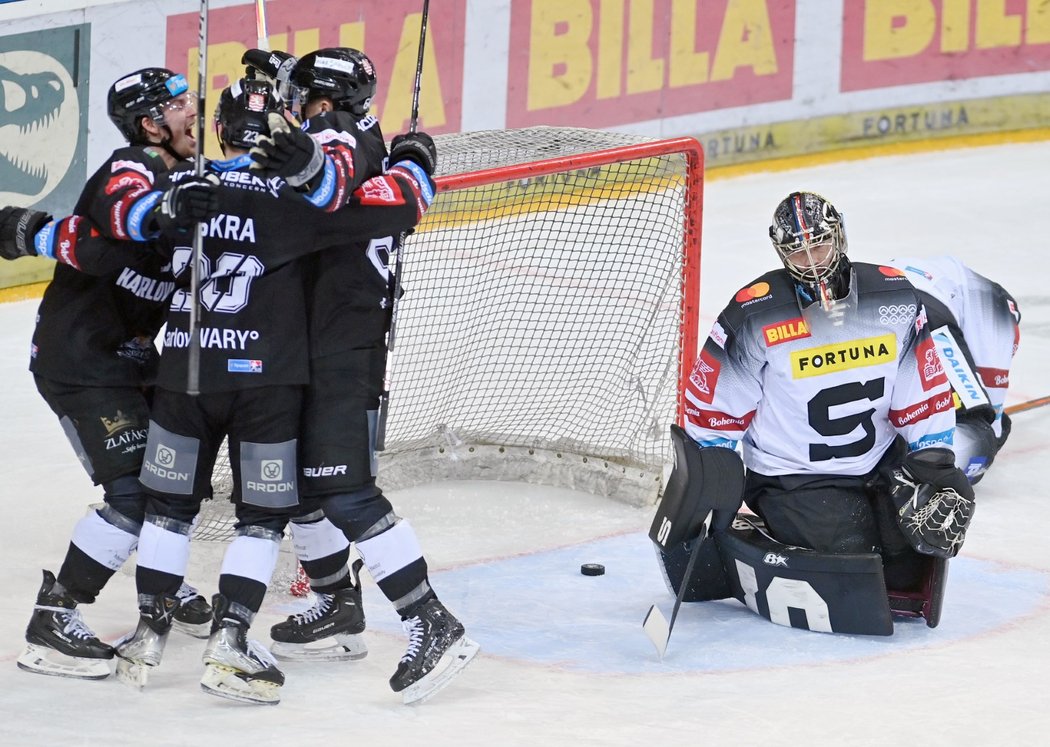 Brankář Sparty Jakub Kovář smutní po inkasované brance vedle radujících se hráčů Karlových Varů