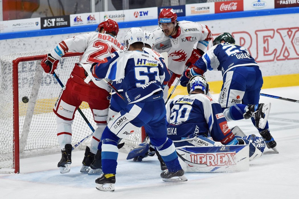 Třinecký útočník Martin Růžička dostává puk za brankáře Komety Karla Vejmelku