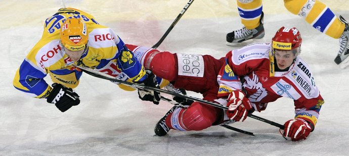 Zlínský Lukáš Galvas (vlevo) a třinecký Jakub Orsava leží na ledě po srážce v boji o puk.