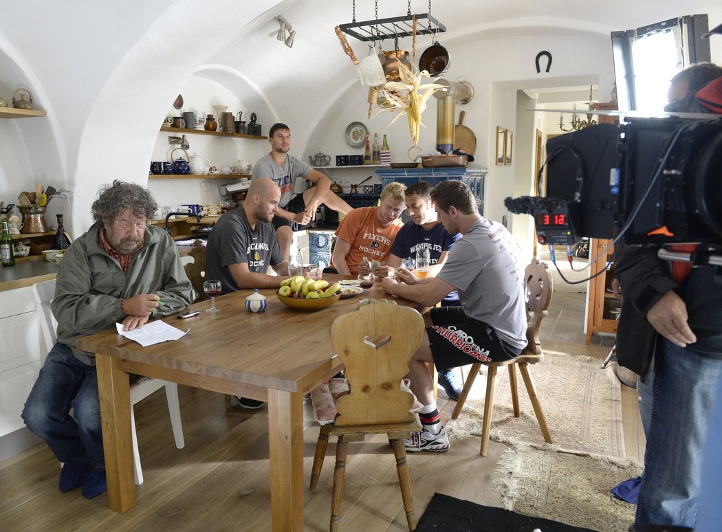 Režisér Zdeněk Troška (vlevo) přemítá nad poznámkami, zatímco pět jeho herců-hokejistů se připravuje na další scénu