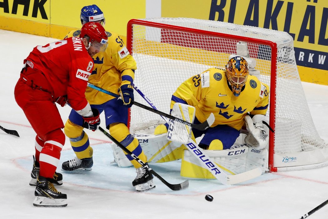 Alexander Ovečkin (vlevo) v souboji před brankou s Erikem Gustafssonem (uprostřed). Situaci přihlíží švédský gólman Jacob Markstrom (vpravo)