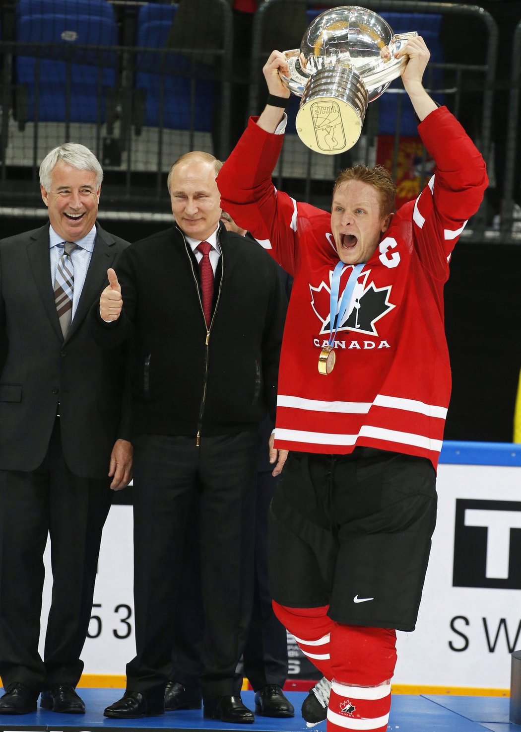 Kanadský kapitán Corey Perry zvedá pohár pro mistry světa, zatímco za ním ruský prezident Vladimir Putin ukazuje palcem jedničku