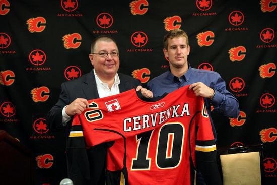 Roman Červenka na tiskové konferenci pózuje spolu s generálním manažerem Calgary Jayem Feasterem a svým dresem s číslem 10