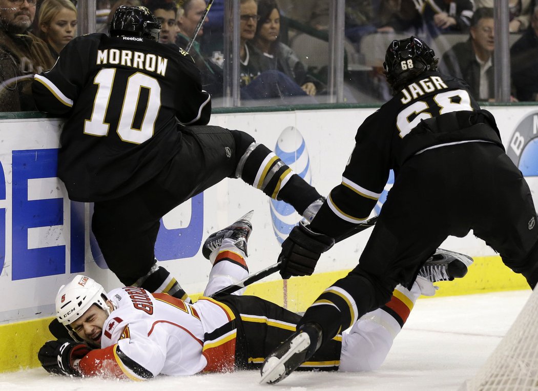 Obránce Flames Mark Giordano úpí na ledě po střetu s Morrowem a Jágrem.