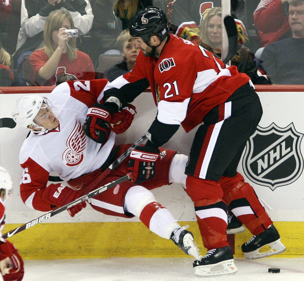 Ottawský Jason Smith sráží u mantinelu českého útočníka Jířího Hudlera v dresu Red Wings.