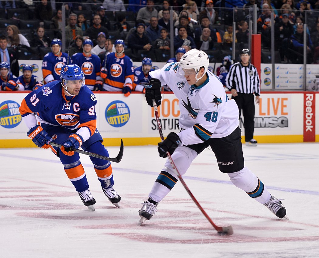 2015. Tomáš Hertl střílí před kapitánem New York Islanders Johnem Tavaresem...