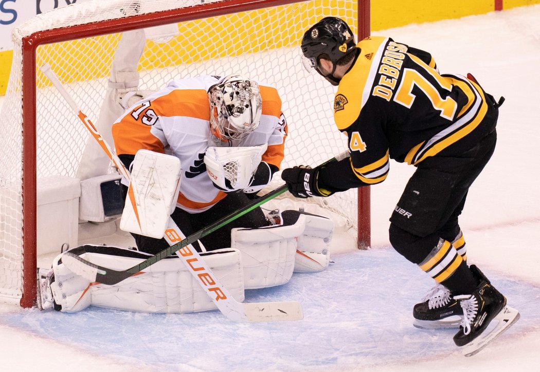 Carter Hart likviduje kotouč před clonícím Jakem DeBruskem z Bostonu