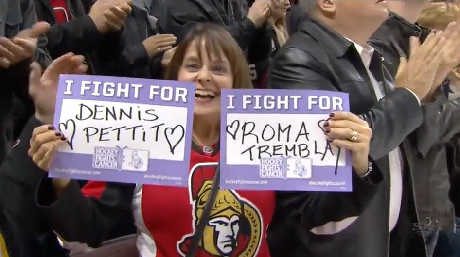 Fanynka v nočním utkání Ottawy proti Calgary ukazuje jména těch, které aspoň na dálku podporuje.