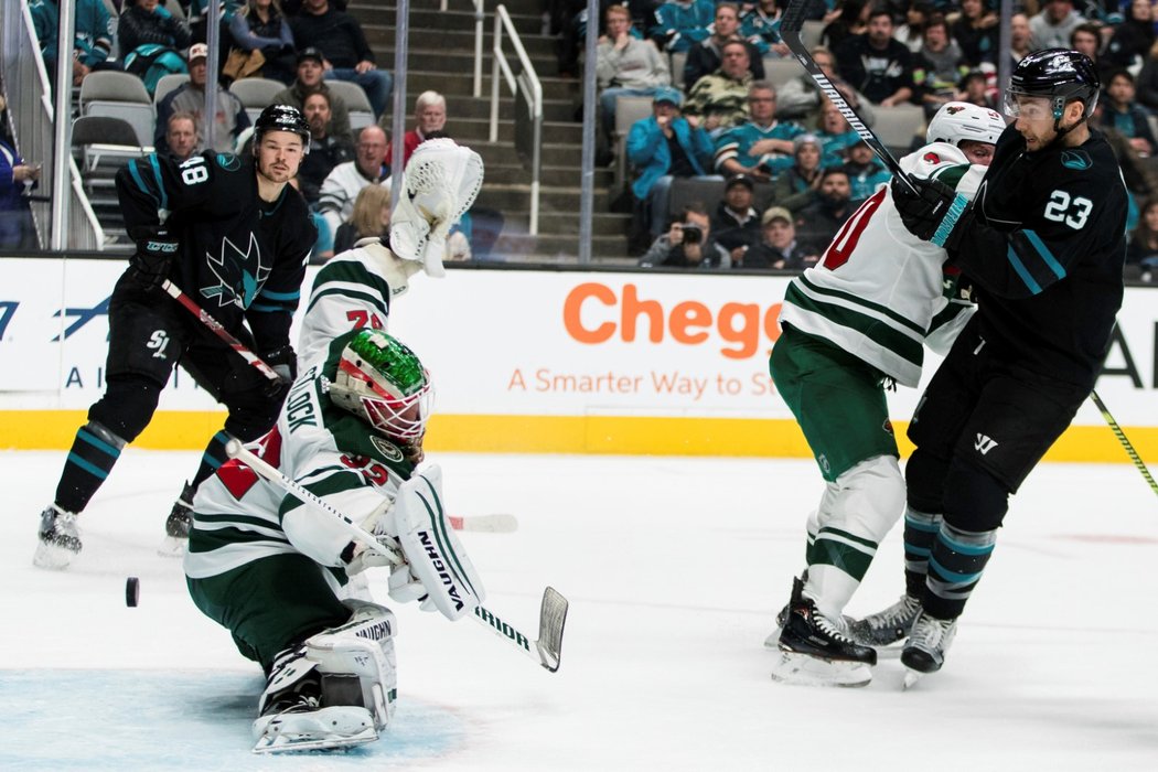 Tomáš Hertl sleduje kotouč, který se po střele Radima Šimka dostal za záda brankáře Alexe Stallocka z Minnesoty