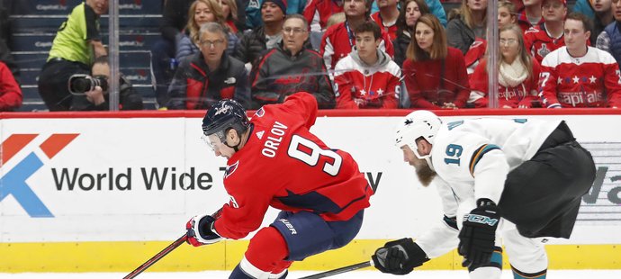 Joe Thornton se snaží dosáhnout až na kotouč, který má v držení Dmitrij Orlov z Washingtonu