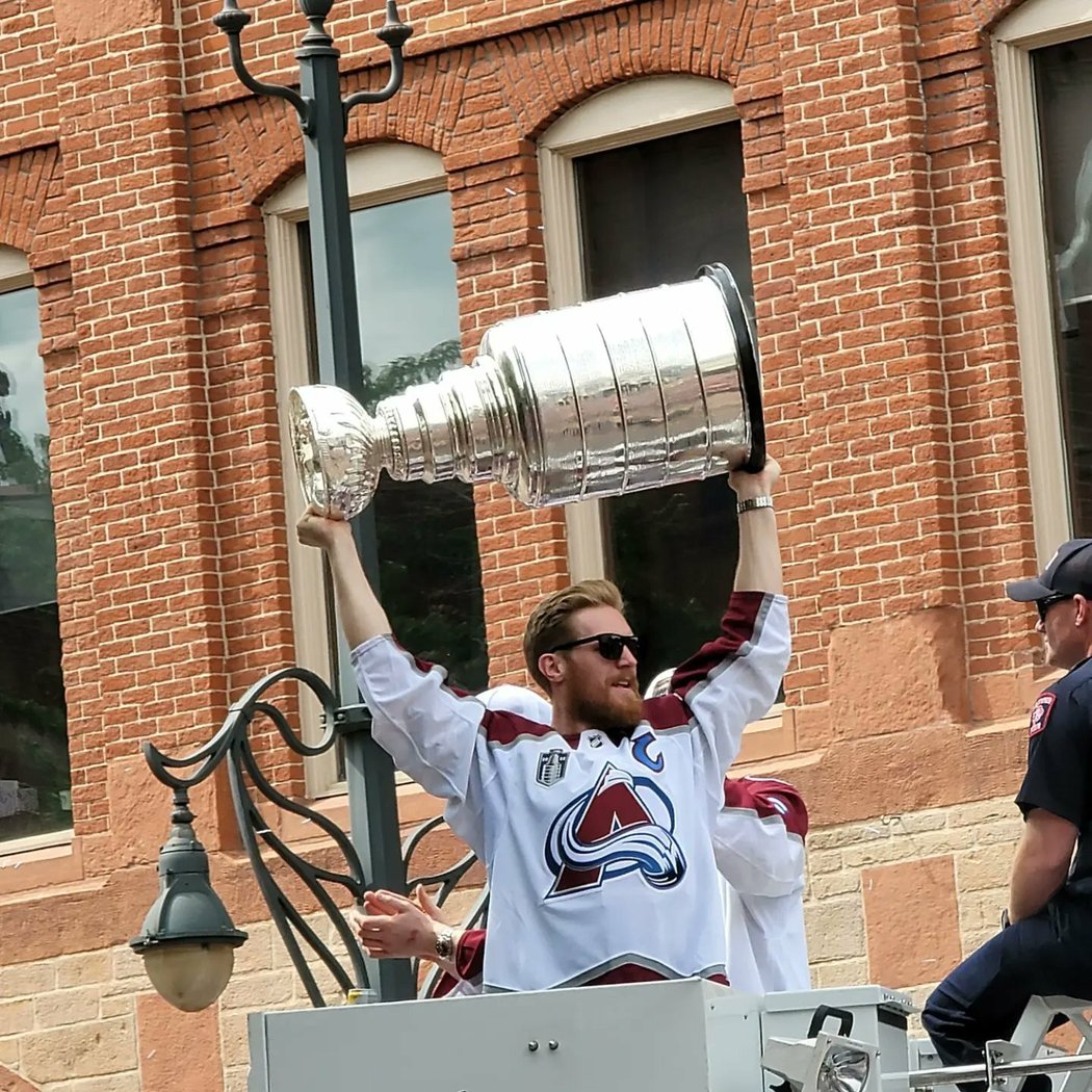 Kapitán Colorada Gabriel Landeskog zvedá nad hlavu Stanley Cup před zraky fanoušků v ulicích Denveru