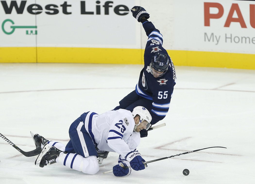 Eric Fehr z Toronta na ledě krotil kotouč před padajícím Markem Scheifelem z Winnipegu