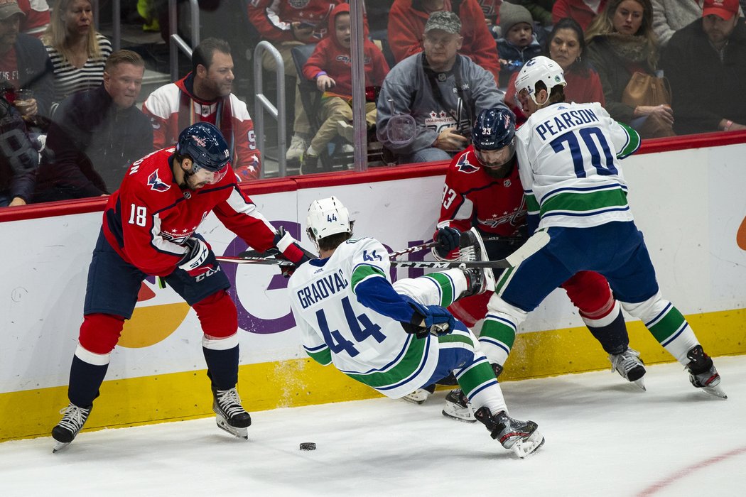 Radko Gudas a jeho spoluhráč Chandler Stephenson se snaží dostat puk od hráčů Canucks