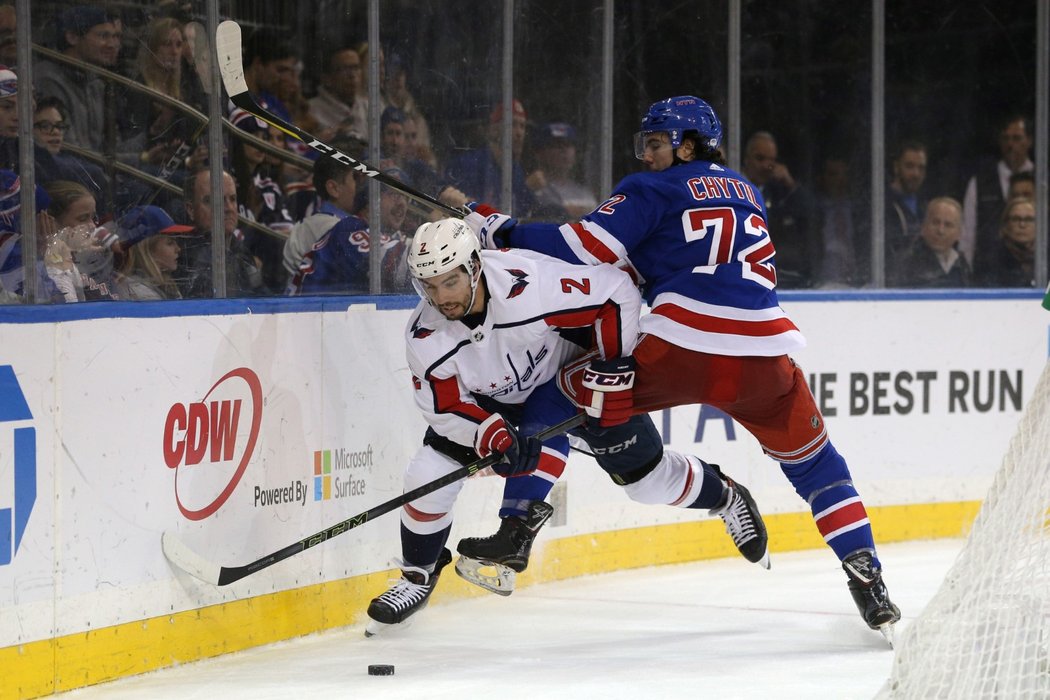 Český útočník Filip Chytil z New York Rangers se u mantinelu snaží zastavit washingtonského obránce Matta Niskanena