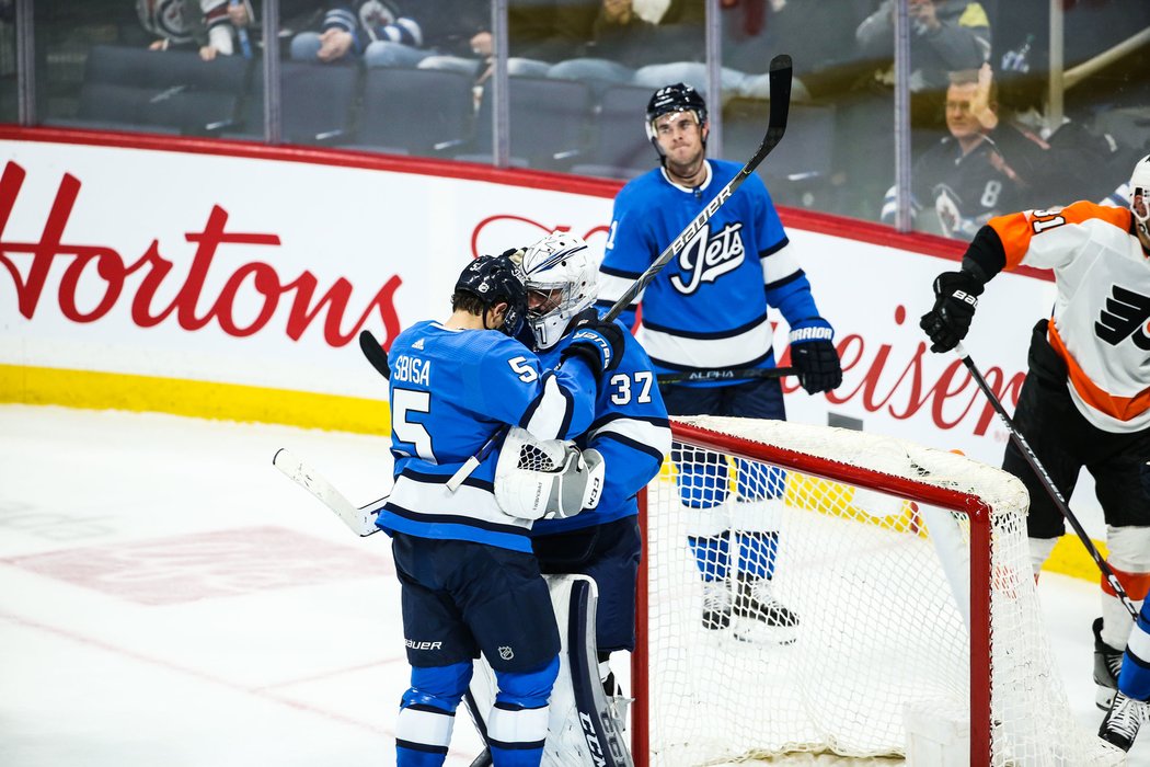 Connor Hellebuyck přijímá gratulaci k šestnácté výhře sezony, obránce Luca Sbisa zase přispěl gólem