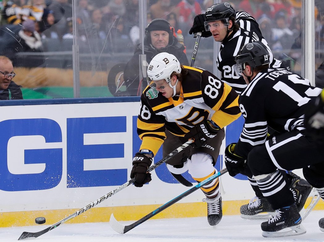 David Pastrňák se snaží zbavit dvojího bránění v podání Jonathana Toewse a Brandona Saada z Chicaga v utkání novoročního Winter Classic