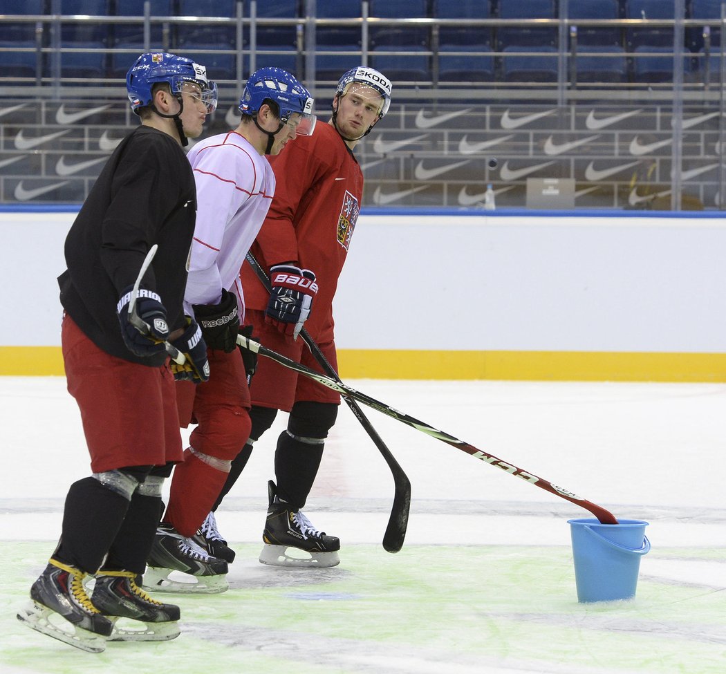 Hokejisté po tréninku uklízejí puky z ledu