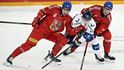 Čeští hokejisté Libor Hájek (vlevo) a Filip Chlapík se snaží obrat finského soupeře