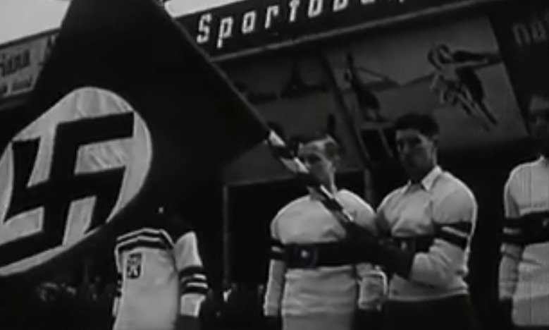 Na 12. mistrovství světa v ledním hokeji konané v Praze přijeli Němci s nacistickou zástavou. Vyhrocenou atmosféru ještě víc umocnilo, když němečtí hokejisté při úvodním nástupu hajlovali