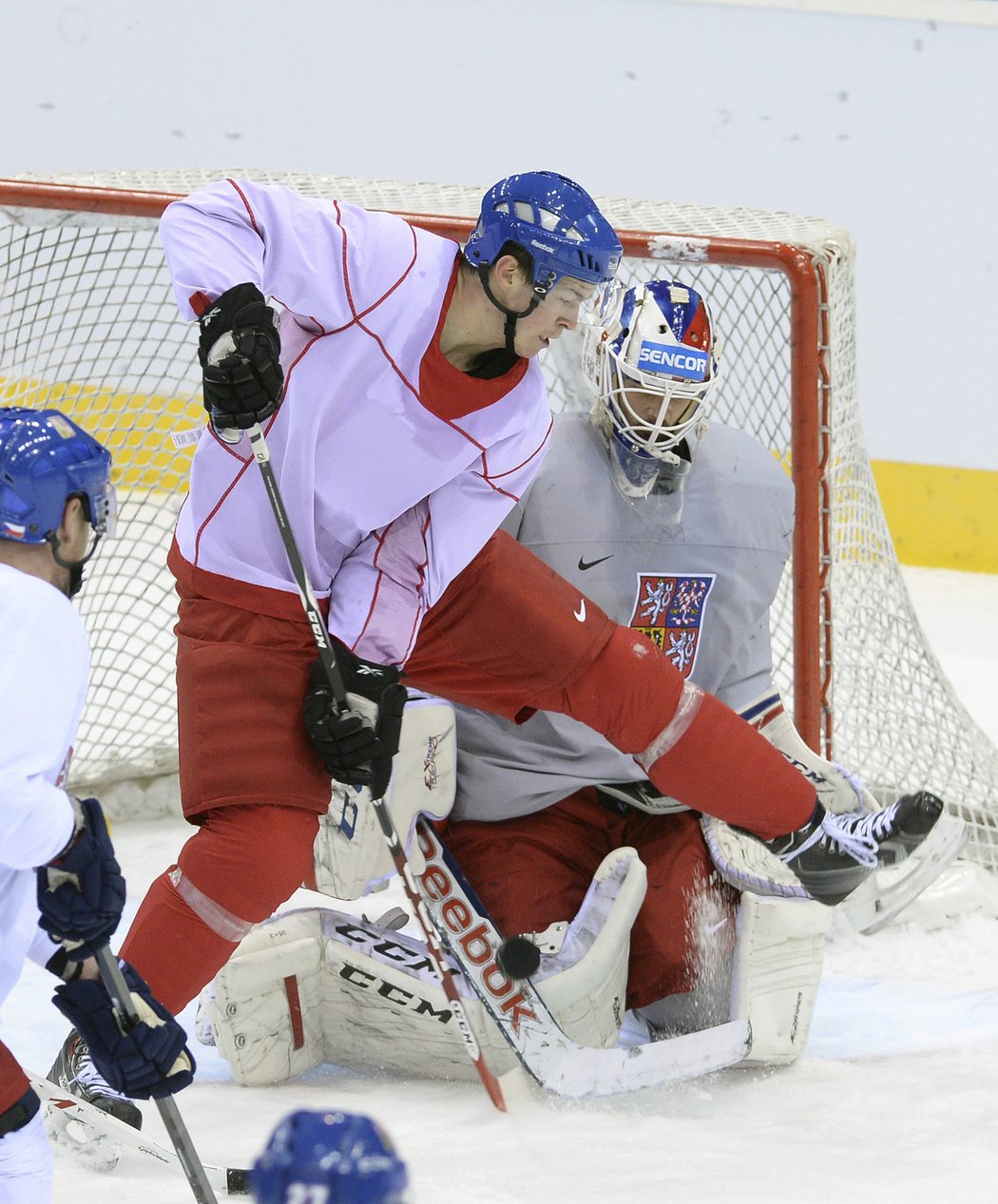 Tomáš Hertl se na tréninku v Minsku snaží trefit puk s hokejkou mezi nohama před brankářem Salákem
