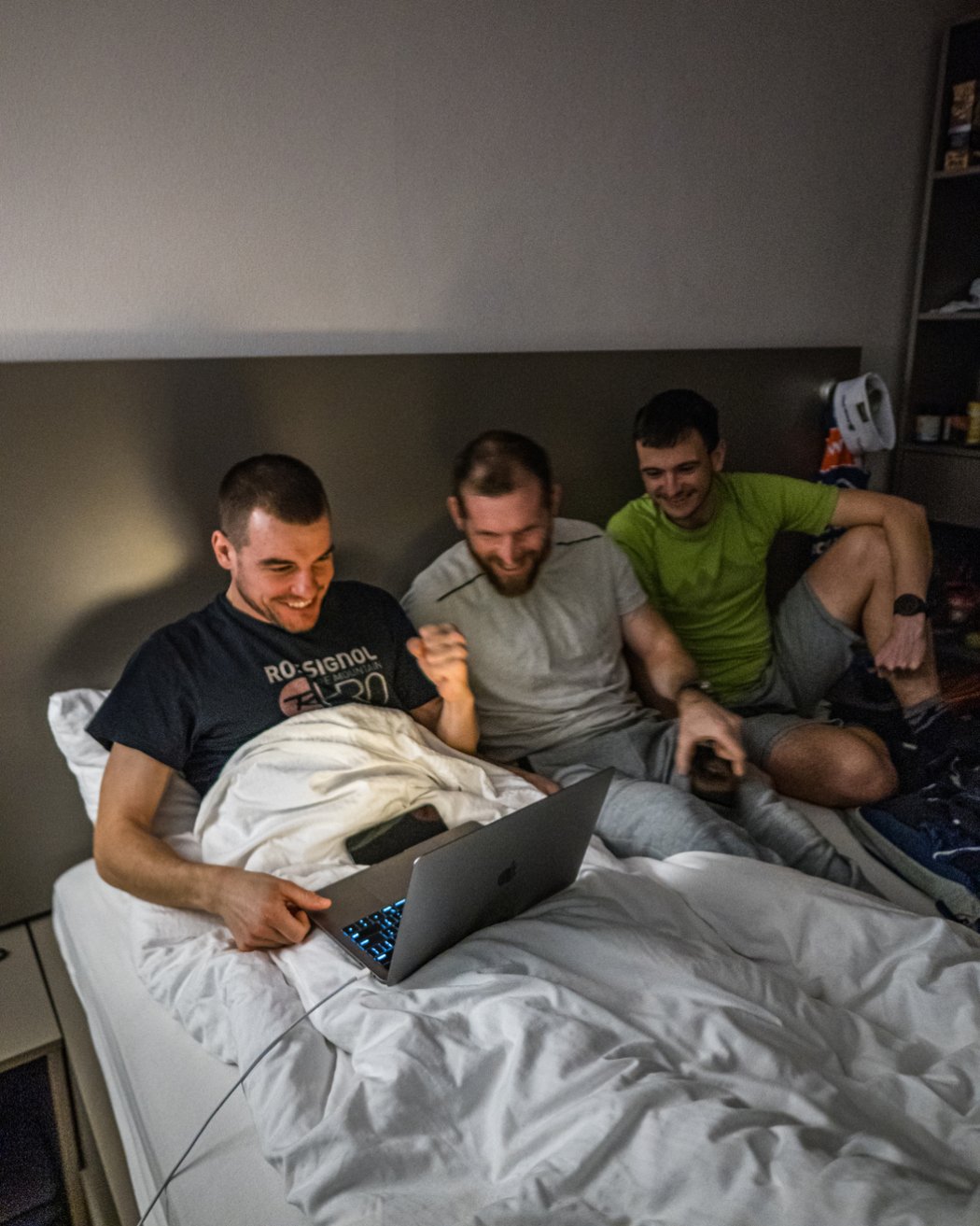Biatlonista Michal Krčmář s dalšími členy české výpravy na Světovém poháru ve Slovinsku z postele sledují hokejové semifinále mezi Českem a Švédskem
