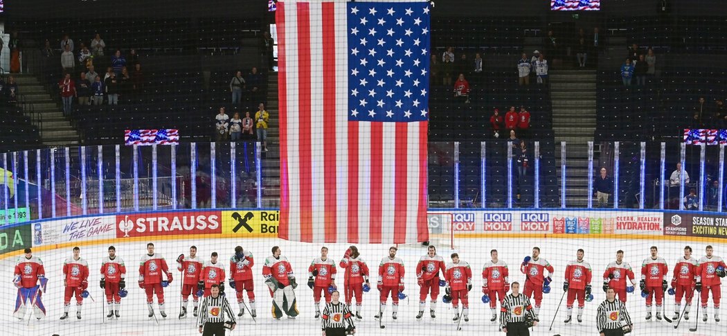 Smutnící čeští hokejisté přihlížejí, jak ke stropu stoupá americká vlajka