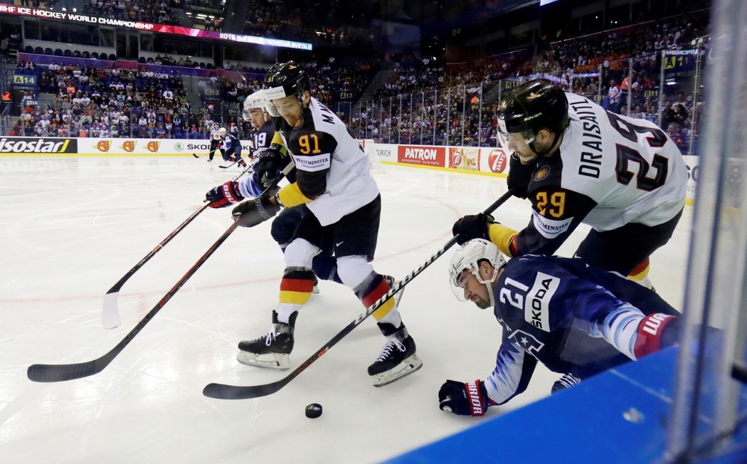 Americký útočník Dylan Larkin bojuje u mantinelu o kotouč proti německé dvojici Leon Draisaitl - Moritz Müller