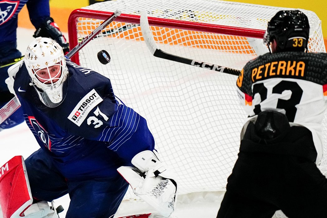 John-Jason Peterka zasahuje letící kotouč před francouzským brankářem Sebastianem Ylönenem