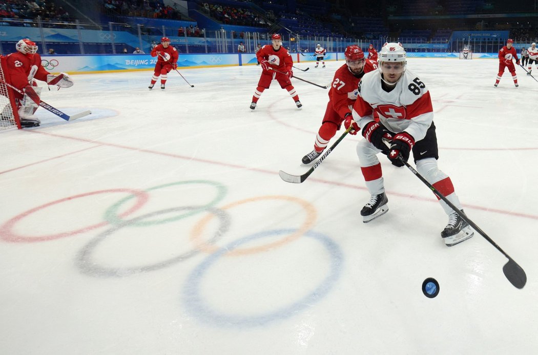 Švýcarský útočník Sven Andrighetto si kryje puk před Vjačeslavem Vojnovem