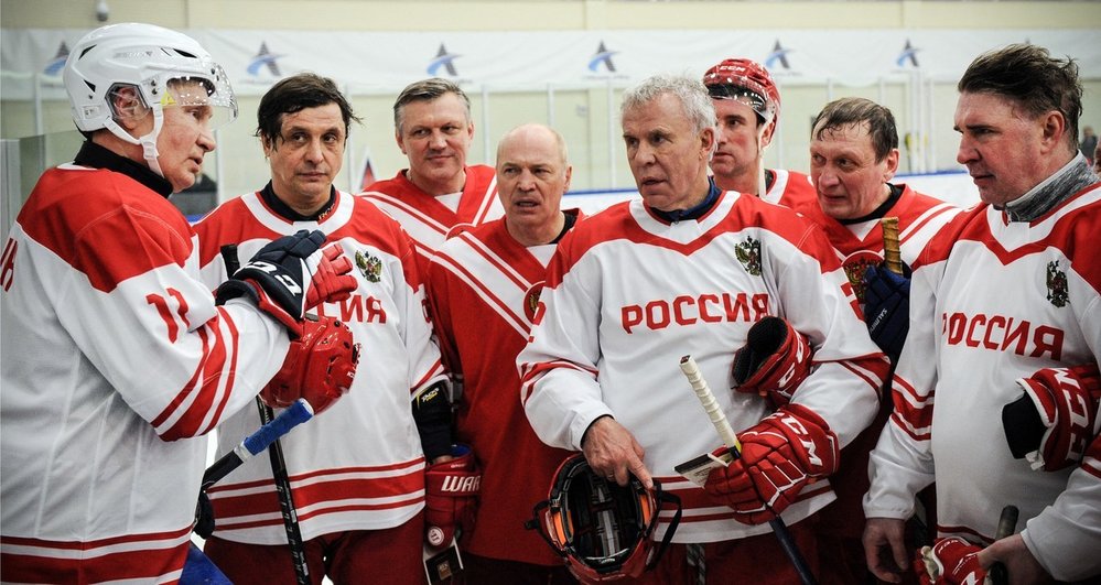 Vladimir Putin (vlevo) promlouvá ke svému týmu během hokejové exhibice