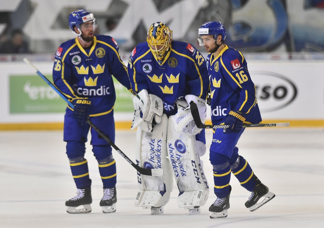 Erik Gustafsson a Marcus Krüger ze Švédska odvádějíí na střídačku otřeseného brankáře Jacoba Markströma