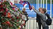 Jeden z malých fanoušků hází svou šálu Lokomotivu na hromadu květin a dalších vzpomínkových předmětů před hokejovou arénou v Jaroslavli