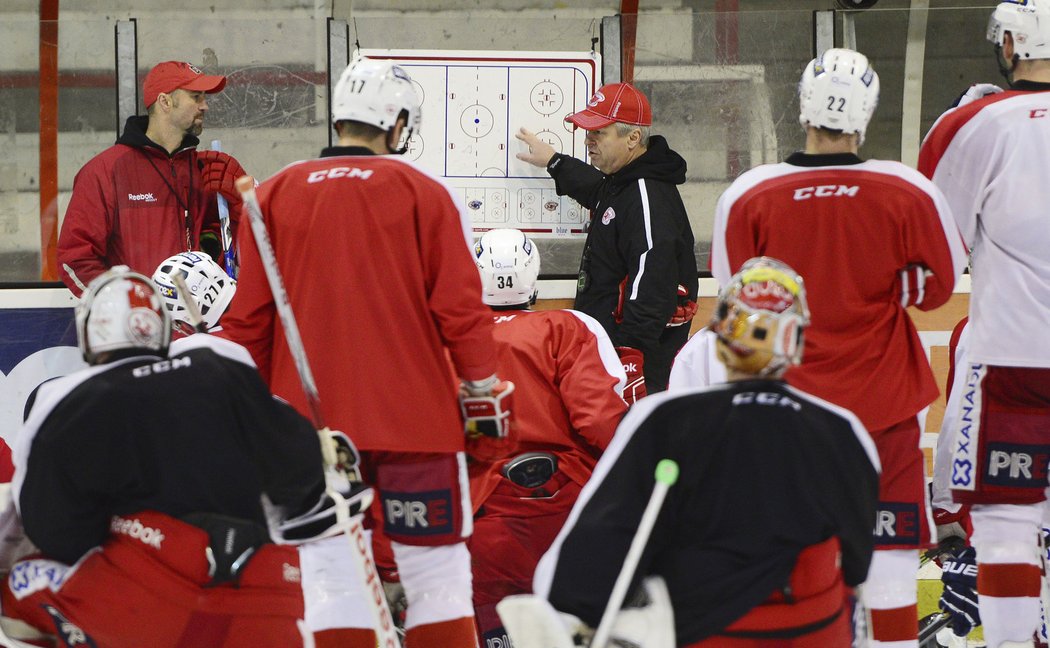 Slovenský trenér hokejové Slavie na tréninku, hráči pozorně naslouchají jeho pokynům.