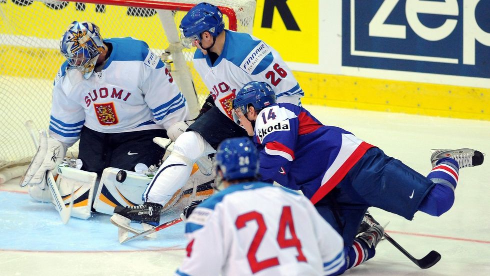 Slovenský útočník Štefan Růžička v souboji s Finem Jarkko Immonenem před brankářem Rinnem.