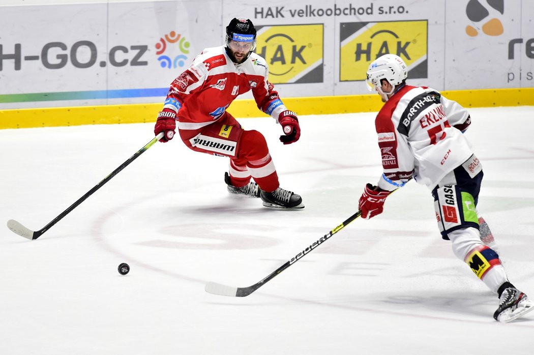 Pardubický obránce Oscar Eklund se snaží odehrát puk před útočníkem Olomouce Petrem Kolouchem