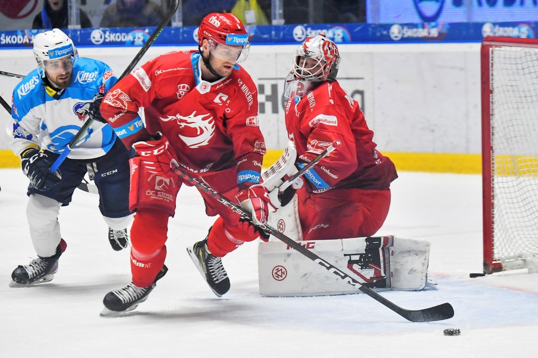 Jakub Jeřábek z Třince vyváží kotouč z brankoviště Marka Mazance, pronásleduje ho plzeňský Filip Suchý