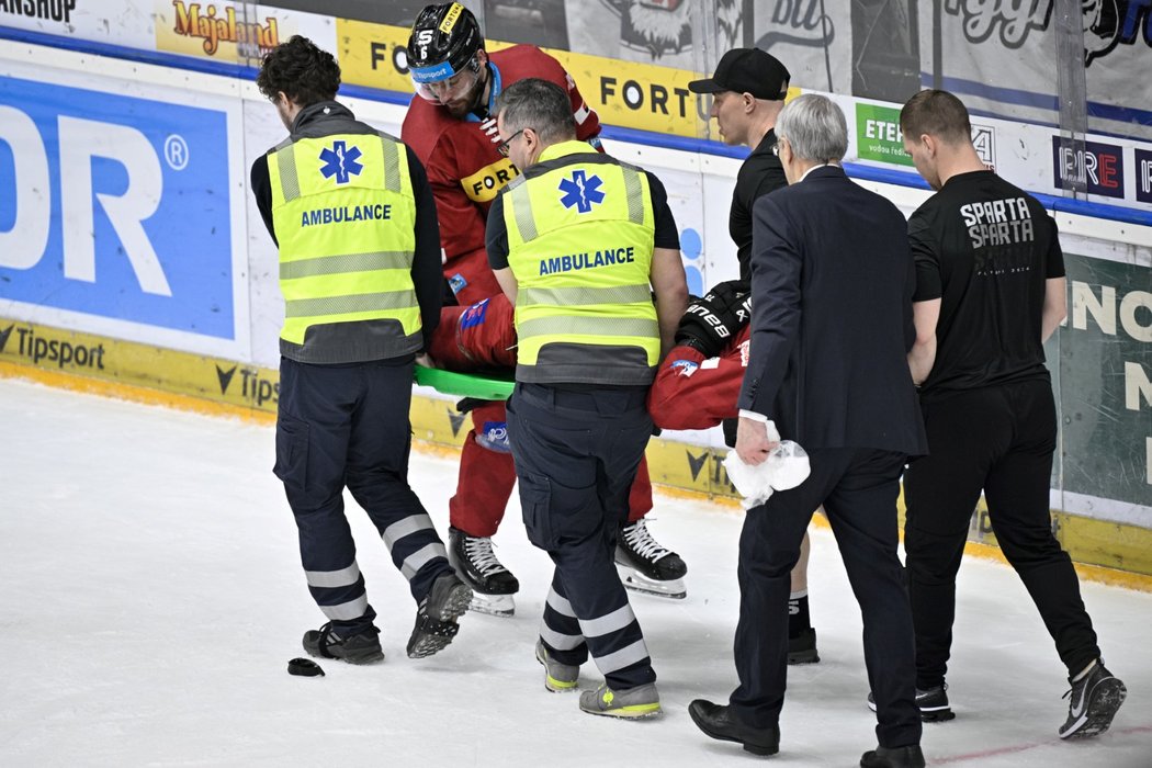 Zraněný obránce Michal Moravčík opouští ledovou plochu na nosítkách
