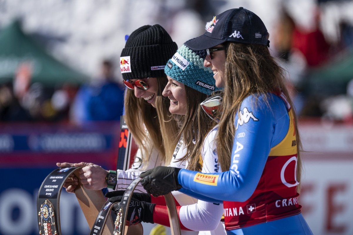 Ester Ledecká, vítězná Švýcarka Priska Nuferová a bronzová Sofia Goggiaová si prohlížejí tradiční zvony, které vyfasovaly na stupně vítězů v Crans Montaně